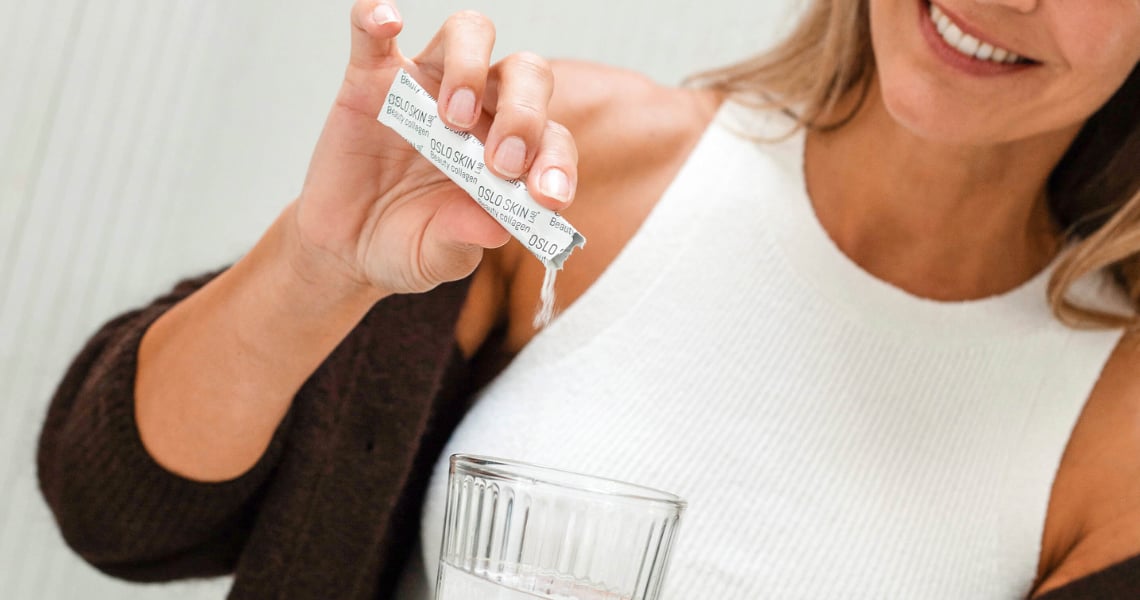 Gros plan d'une femme qui verse un stick de collagène The Solution dans un verre