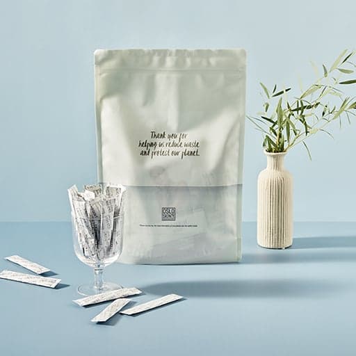 Photo d'un sachet The Solution Refill avec sticks dans un verre